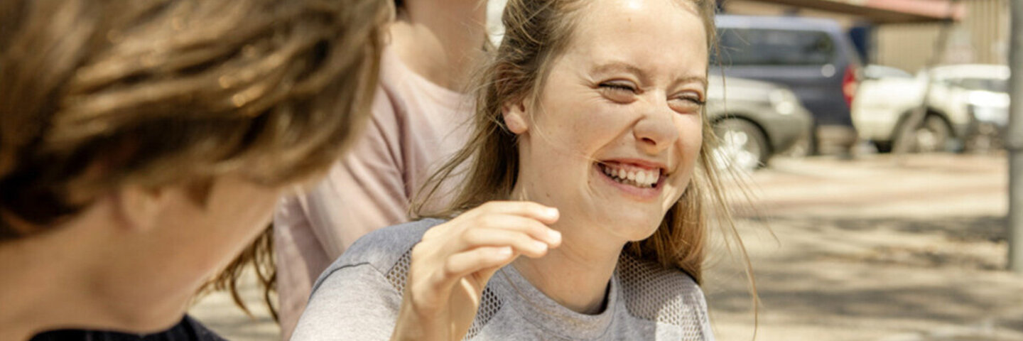 Teenagerin lacht beherzt mit ihren Freunden, weil sie weiß, Lachen ist gesund.