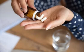 Eine Frau schüttet eine Pillenfalsche in der Hand aus.