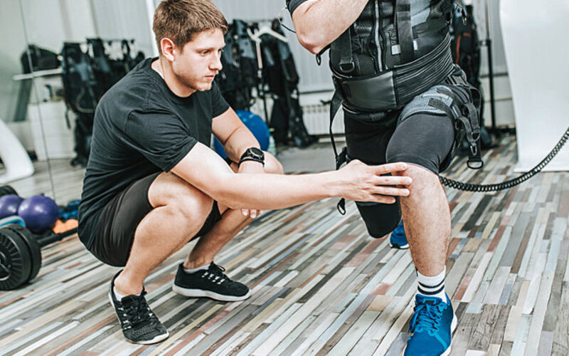 Personal Trainer unterstützt Sportler beim EMS-Training.