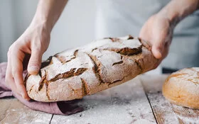 Mann hält selbstgebackenes Sauerteigbrot.