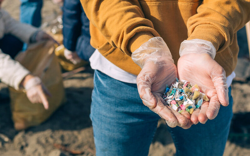 Umweltschützer sammelt Plastik am Strand, um die Zersetzung zu Mikroplastik zu verhindern.
