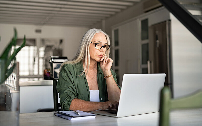 Eine Frau sitzt am Laptop und beschäftigt sich mit Online-Selbsthilfe-Angeboten.