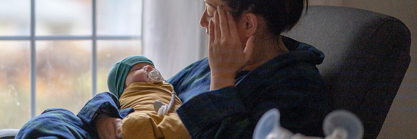 Mutter hält trauernd ihr Neugeborenes im Arm, da sie an einer postpartalen Depression leidet.