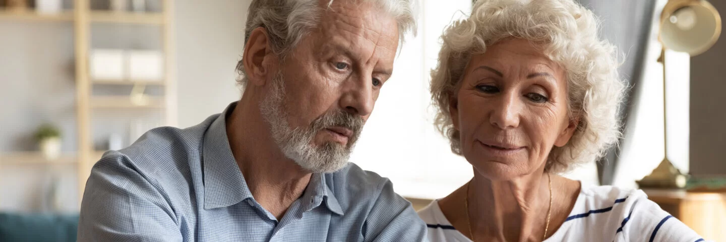 Ein älteres Paar schaut gemeinsam auf eine Liste von Anbietern für Pflegehilfsmittel.