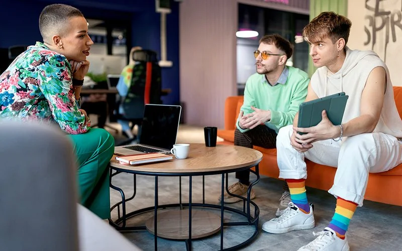 Drei Personen unterhalten sich bei einem Meeting im Büro und schauen auf ein Tablet.