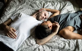 Ein homosexuelles Paar kuschelt im Bett und redet über Erektionsprobleme.