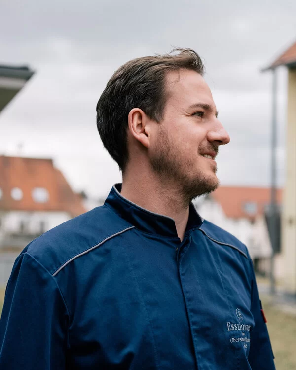 Ein Koch der die AOK-Kochshow in Laupheim moderieren wird, schaut unter freiem Himmel in die Ferne.