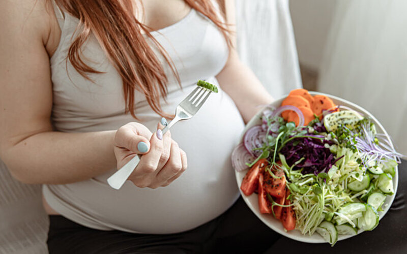 Eine Schwangere mit Schwangerschaftsdiabetes isst viel frisches Gemüse.