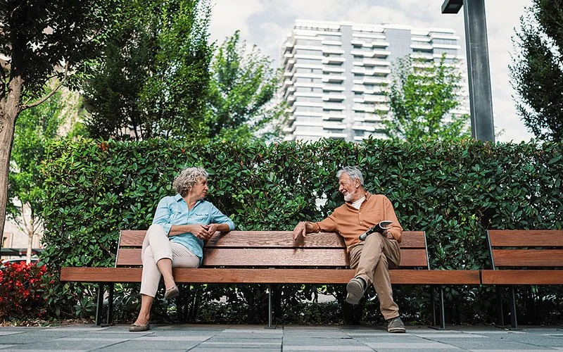 Eine Frau und ein Mann unterhalten sich auf einer Bank in einer Stadt.