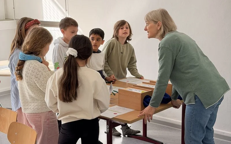 Lehrkraft begleitet Schülerinnen und Schüler bei einer interaktiven Gruppenaufgabe zur Gesundheitsförderung im Rahmen von Ahorn@school.