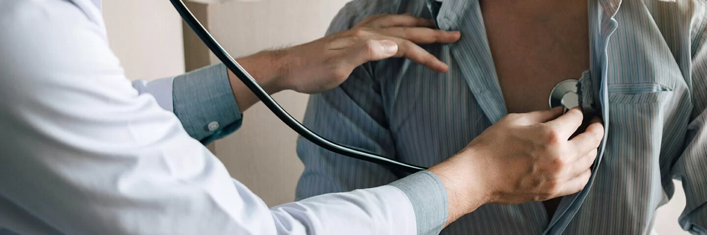 Ein Arzt hört das Herz eines Mannes mit einem Stethoskop ab.