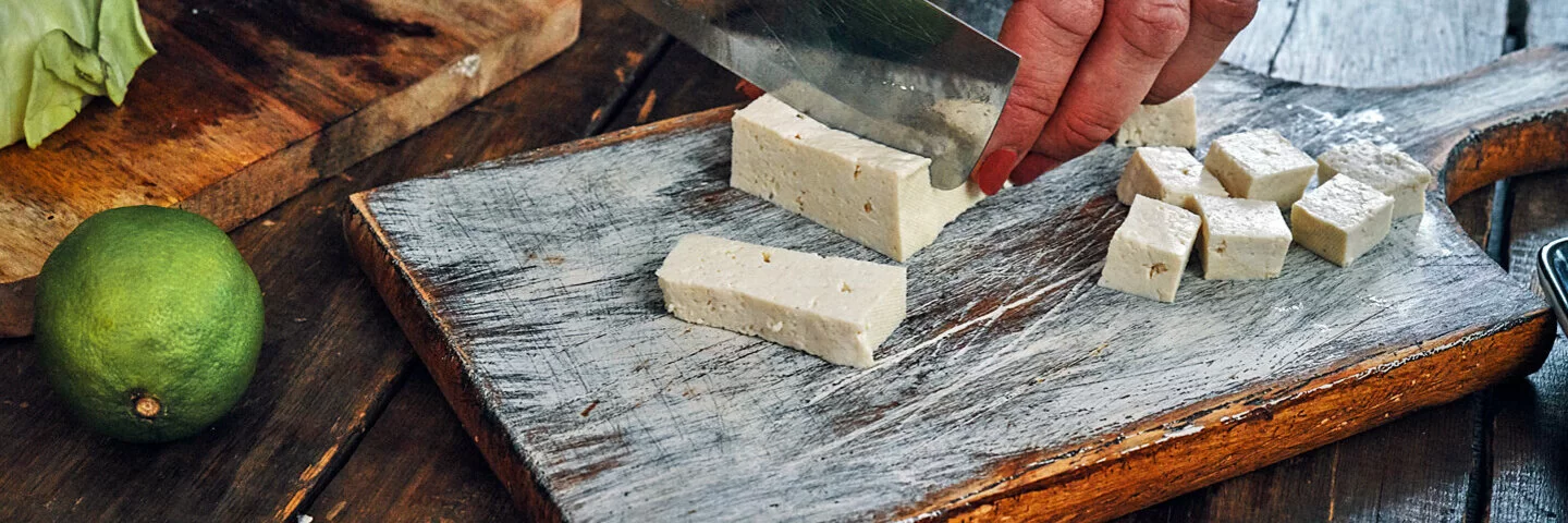 Ein Mann schneidet Tofu in kleine Würfel.