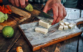 Ein Mann schneidet Tofu in kleine Würfel.