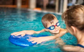 Kleiner Junge beim Schwimmunterricht im Hallenbad.