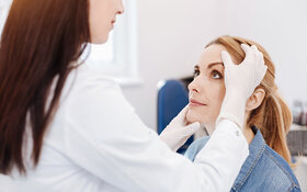 Ärztin untersucht junge Frau auf Plattenepithelkarzinom, eine Form des weißen Hautkrebs.