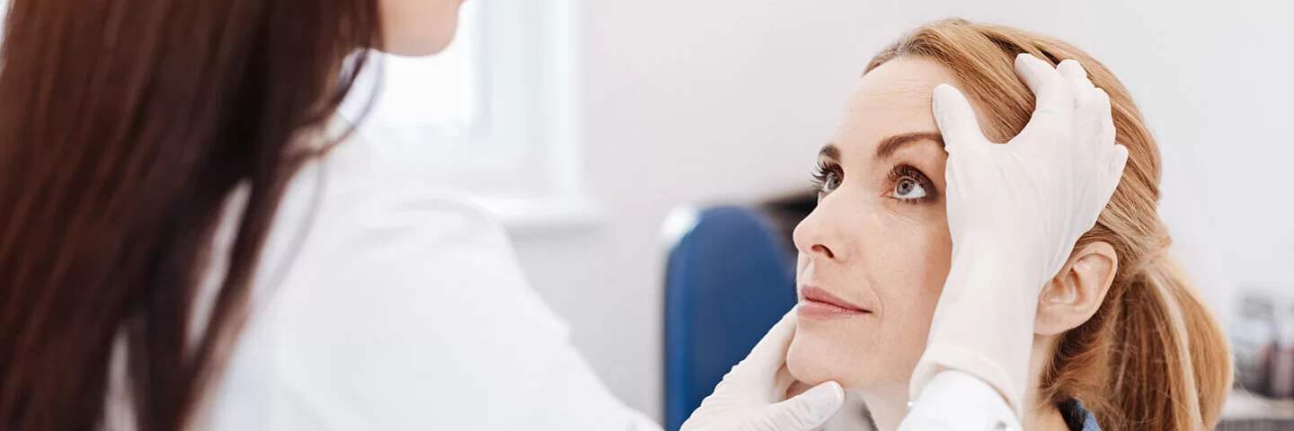 Ärztin untersucht junge Frau auf Plattenepithelkarzinom, eine Form des weißen Hautkrebs.