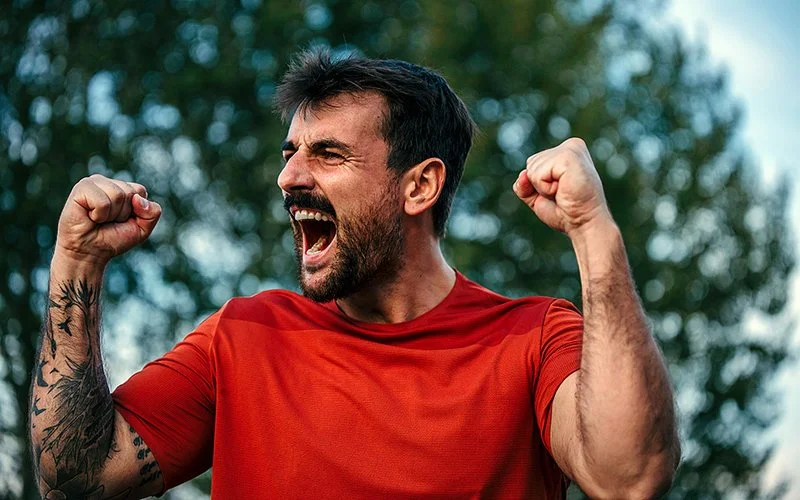 Ein Mann reckt die geballten Fäuste in die Luft und freut sich.