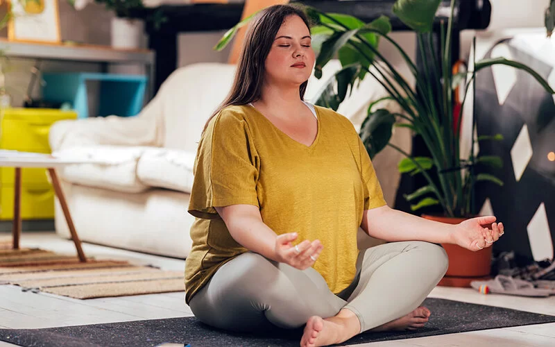 Junge Frau macht nach ihrem Retreat-Urlaub Yoga zu Hause.