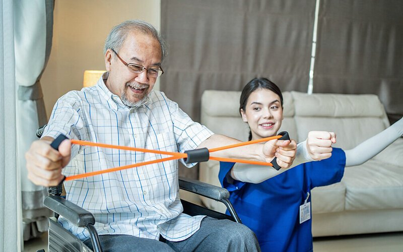 Älterer Mann trainiert im Rahmen von aktivierender Pflege seine Armmuskulatur.