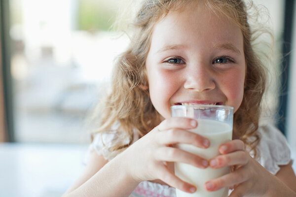 Ein kleines Mädchen trinkt aus einem Glas Milch.