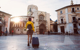 Eine Studentin ist für ihr Auslandsjahr mit ihrem Koffer in Valencia unterwegs.
