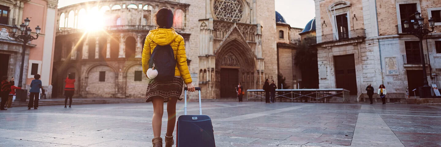 Eine Studentin ist für ihr Auslandsjahr mit ihrem Koffer in Valencia unterwegs.
