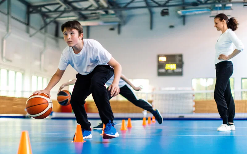 Kinder in einer Sportschule trainieren mit Basketbällen.