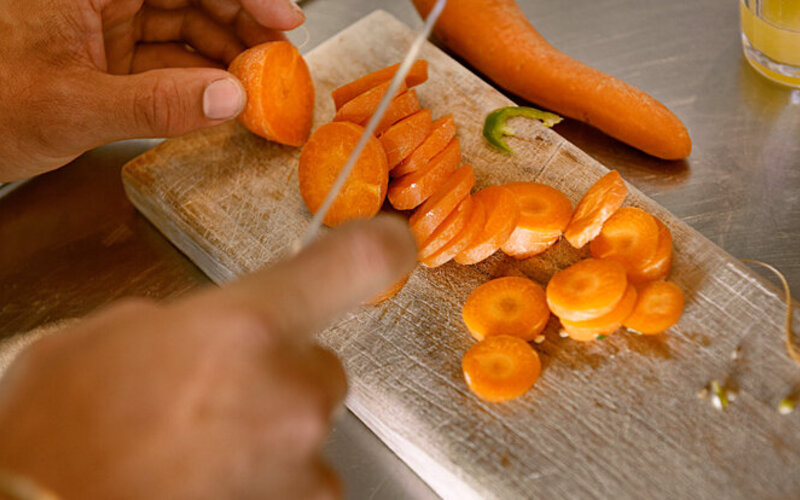 Gemüse schonend zubereiten: Mann schneidet Karotte.