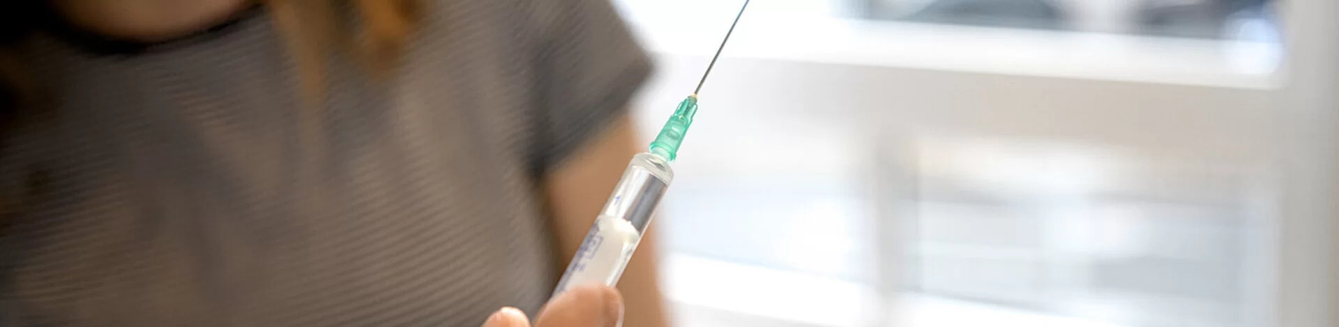 Ein Arzt bereitet eine Spritze für eine Reiseschutzimpfung vor.
