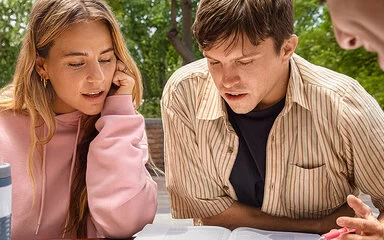 Zwei junge Frauen und zwei Junge Männer sitzen im Freien unter einem Baum. Auch als Studierende sind sie bei der AOK gut versichert.