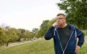Ein Mann steht im Freien und zieht an einer Zigarette. Die AOK hilft Ihnen, Ihre Sucht zu überwinden. 