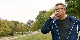 Ein Mann steht im Freien und zieht an einer Zigarette. Die AOK hilft Ihnen, Ihre Sucht zu überwinden. 