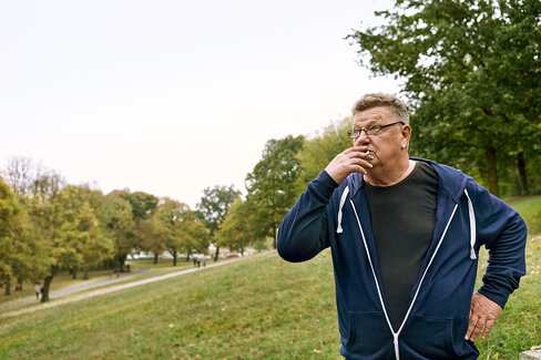 Ein Mann steht im Freien und zieht an einer Zigarette. Die AOK hilft Ihnen, Ihre Sucht zu überwinden. 