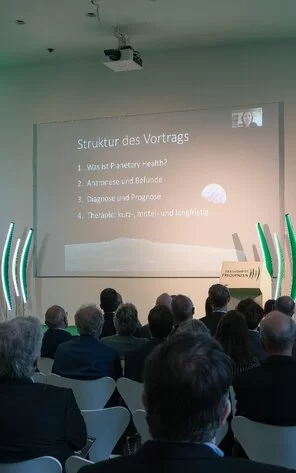Auf dem Bild kann man die Agenda der Veranstaltung sehen, welche auf eine große Leinwand projiziert wird.