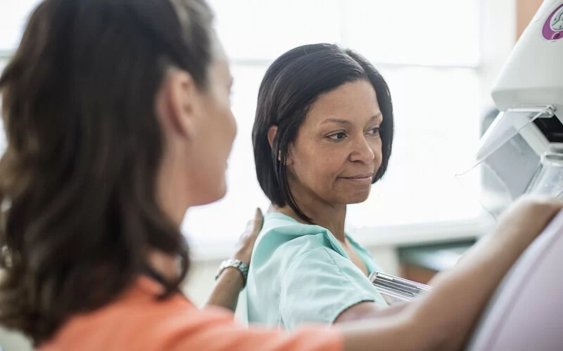 Ärztin stellt Patientin vor ein Mammografie-Gerät, um die Brust zu röntgen.