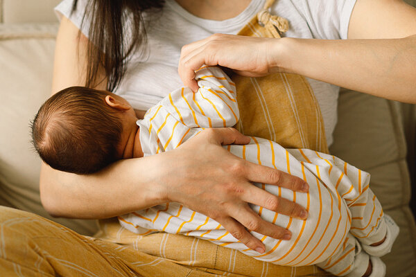 Eine Frau stillt ihr Baby und hat Probleme mit Milchstau.