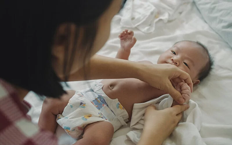 Einschlafhilfe: Mutter zieht Baby Schlafanzug an