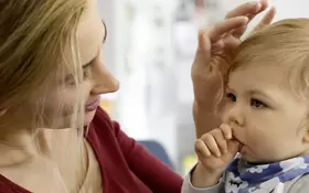 Eine Frau hält ihr Kleinkind, das sich verschluckt hat.