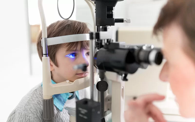 In der Augenärztlichen Praxis werden die Augen eines kleinen Jungen mit einer Spaltlampe untersucht.