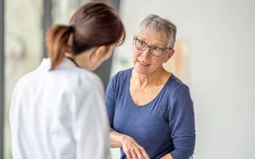 Bei der Herzkatheteruntersuchung spricht eine Frau mit kurzen, grauen Haaren mit ihrer Ärztin.