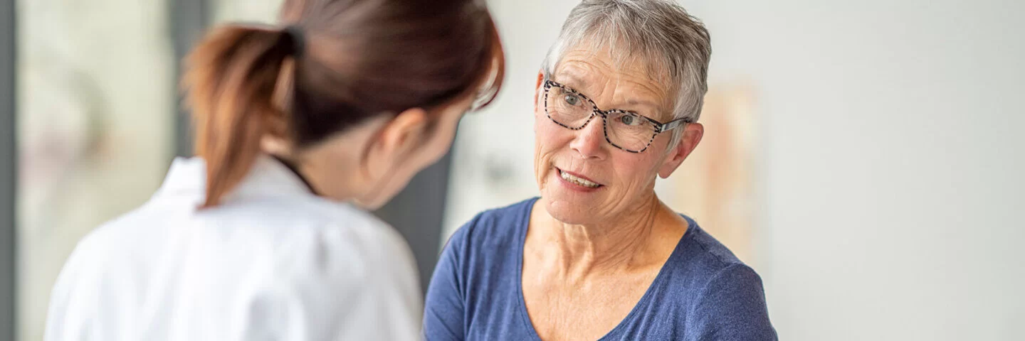 Bei der Herzkatheteruntersuchung spricht eine Frau mit kurzen, grauen Haaren mit ihrer Ärztin.