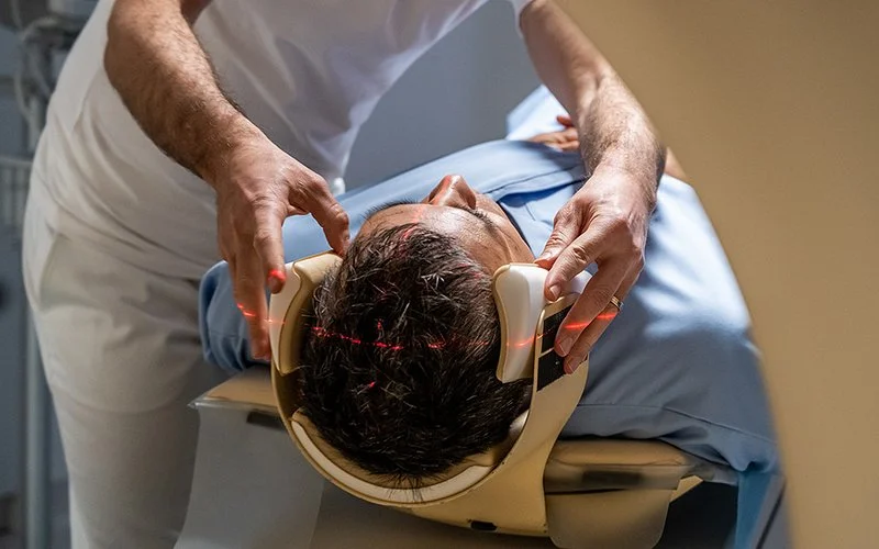 Ein Mann wird von einem Arzt in einen CAT-Scanner geschoben.