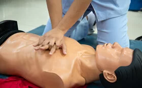 Eine Person übt Herzdruckmassage an einem Erste-Hilfe-Dummy.