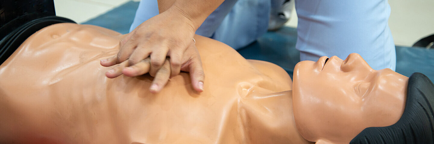 Eine Person übt Herzdruckmassage an einem Erste-Hilfe-Dummy.