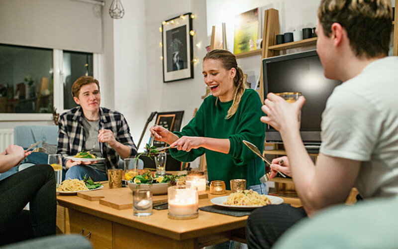 Eine Wohngemeinschaft isst gemeinsam am Tisch und fördert so nachhaltiges Konsumverhalten.