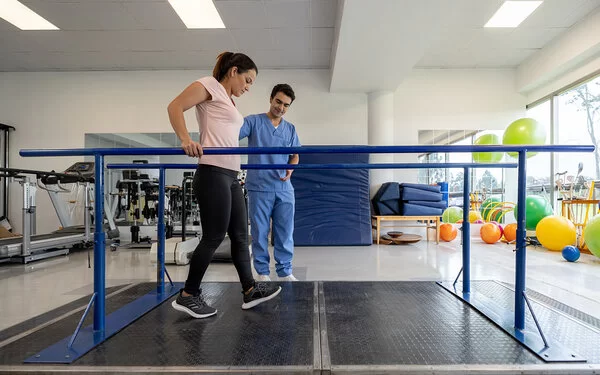 Frau absolviert ein kräftigenden Gehtraining bei einer Rehabilitationsmaßnahme.