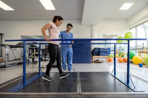 Frau absolviert ein kräftigenden Gehtraining bei einer Rehabilitationsmaßnahme.