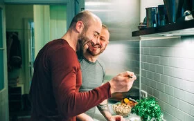 Zwei Männer kochen sich in der Küche ein gesundes veganes Essen.