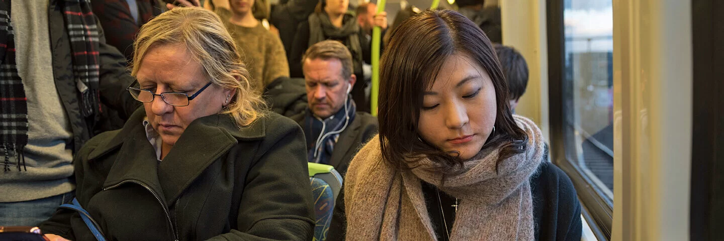 Viele Menschen sitzen und stehen eng an eng in einem Bus.