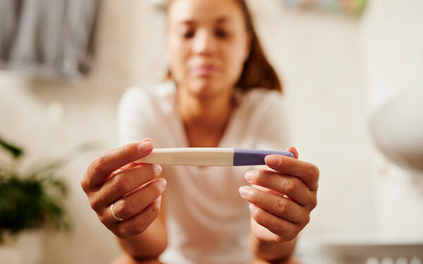 Eine Frau schaut auf einen Schwangerschaftstest.